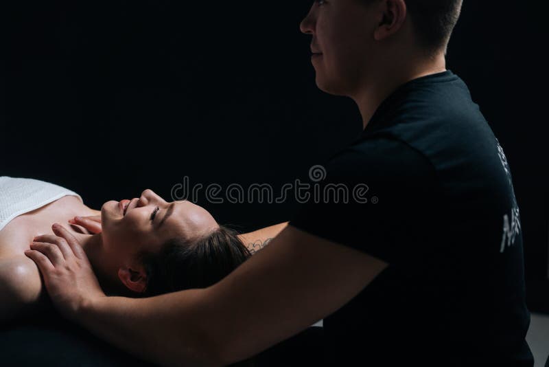 Professional male masseur massages neck and shoulders of young woman in  massage parlor., Stock image