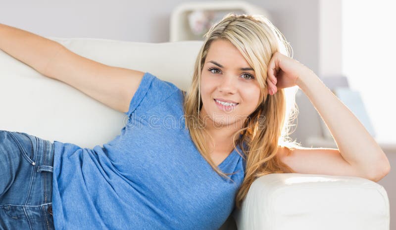 Smiling young woman lying on sofa in living room royalty free stock photo Smiling young woman lying on sofa in living room royalty free stock photo