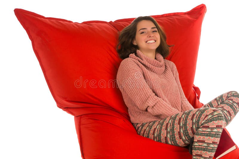 Smiling young woman sitting on red beanbag sofa chair for living