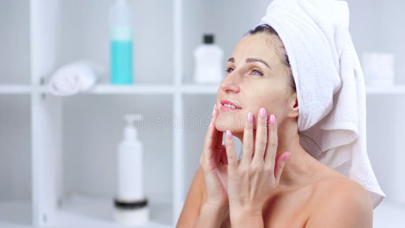 Smiling young woman taking off cosmetic mask and massaging face stock video