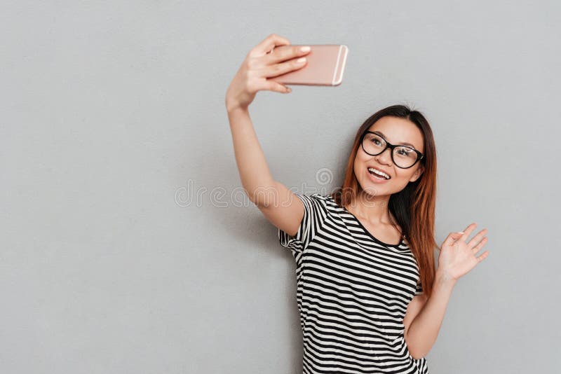 Smiling young woman talking with friends by phone and waving.