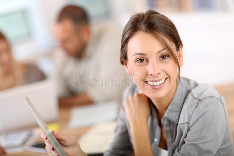 Smiling young woman in training class using tablet