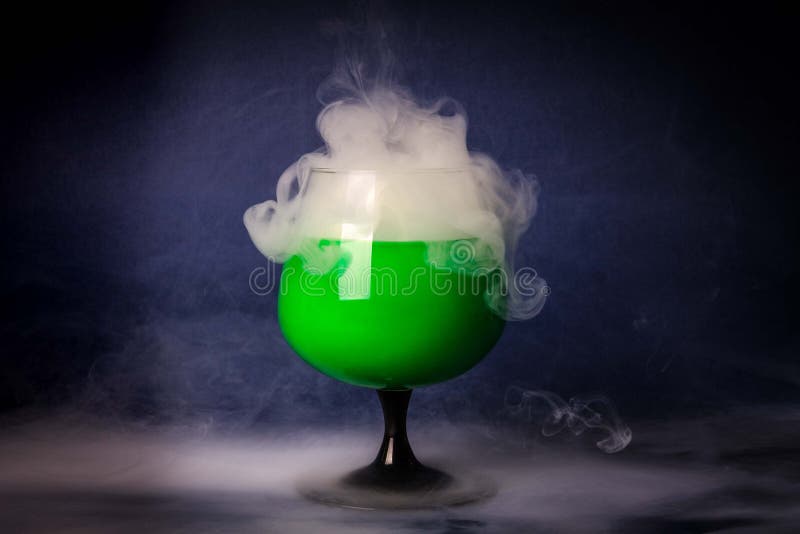 Abstract art. Hookah smoke into cocktail glass on a black background. Witch potion background for Halloween. Unusual bar drink. Drink in the glass with the effect of dry ice.