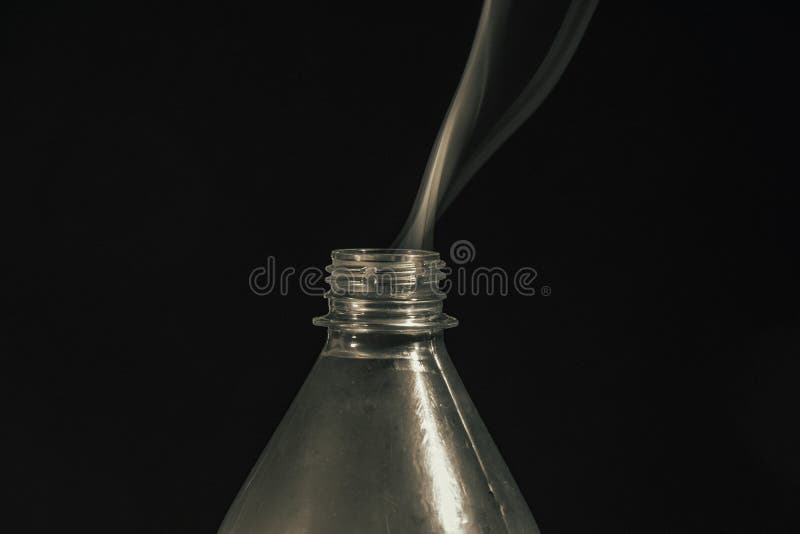 Smoke Coming Out of a Plastic Bottle Against a Black Background Stock
