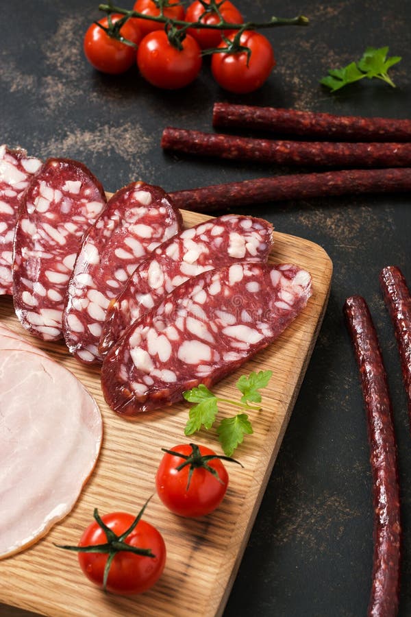 Smoked chopped sausage on a cutting board with cherry tomatoes. stock photo Smoked chopped sausage on a cutting board with cherry tomatoes. stock photo