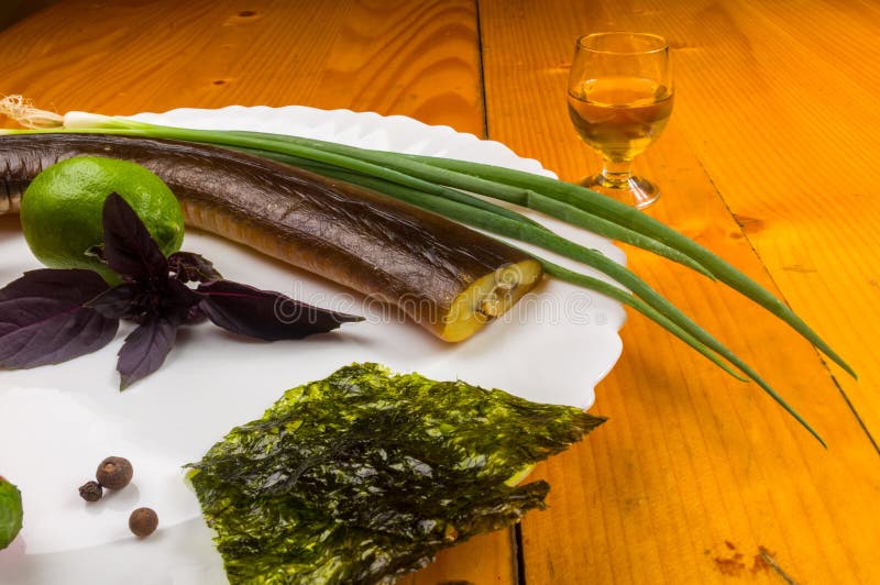smoked garfish with lime, Basil, green onions, chili, nori chips, spices, olive oil in a white ceramic dish, on a wooden table royalty free stock photo smoked garfish with lime, Basil, green onions, chili, nori chips, spices, olive oil in a white ceramic dish, on a wooden table royalty free stock photo