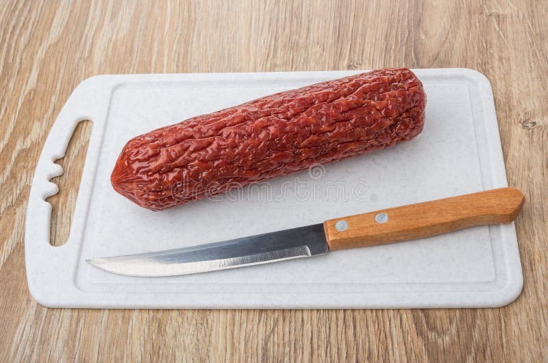 Smoked Sausage and Kitchen Knife on Plastic Cutting Board Stock Image