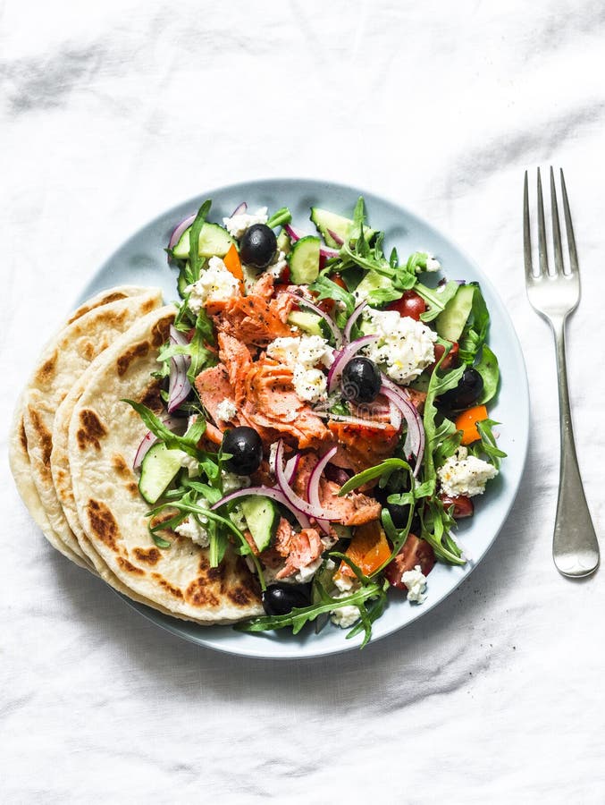 Smoked trout greek salad on a light background, top view. Healthy mediterranean diet food