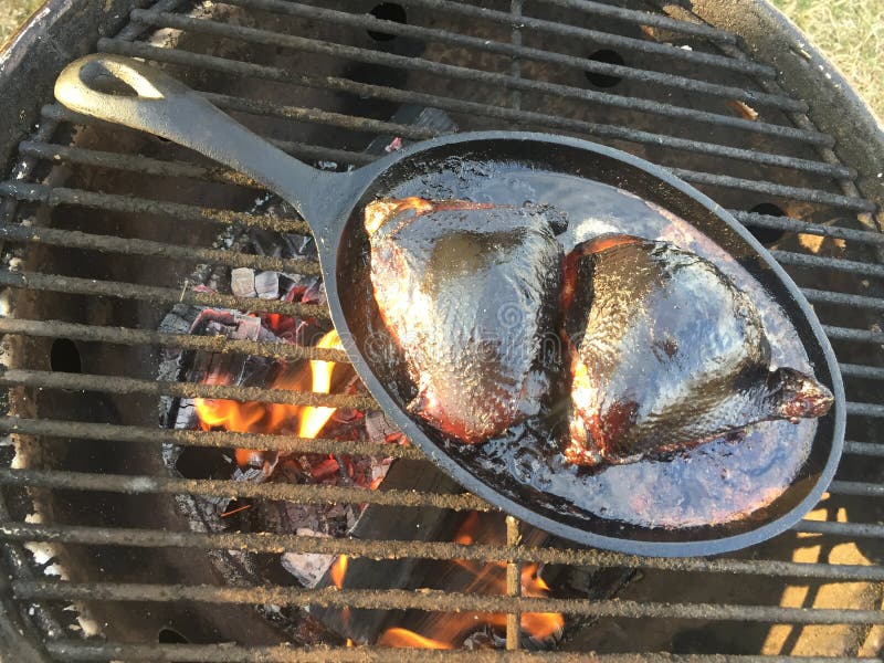 Smoking and Grilling of Two Chicken Legs on an Iron Pan Stock Photo