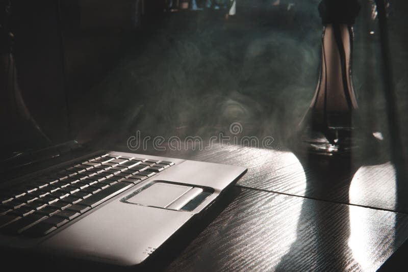 Smoking hookah while working on laptop at home, dark theme, close up, sun light lines stock photo Smoking hookah while working on laptop at home, dark theme, close up, sun light lines stock photo