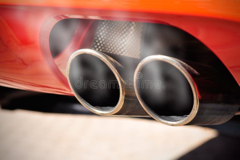 Close up di una macchina rossa di scarico a doppio tubo con il fumo.