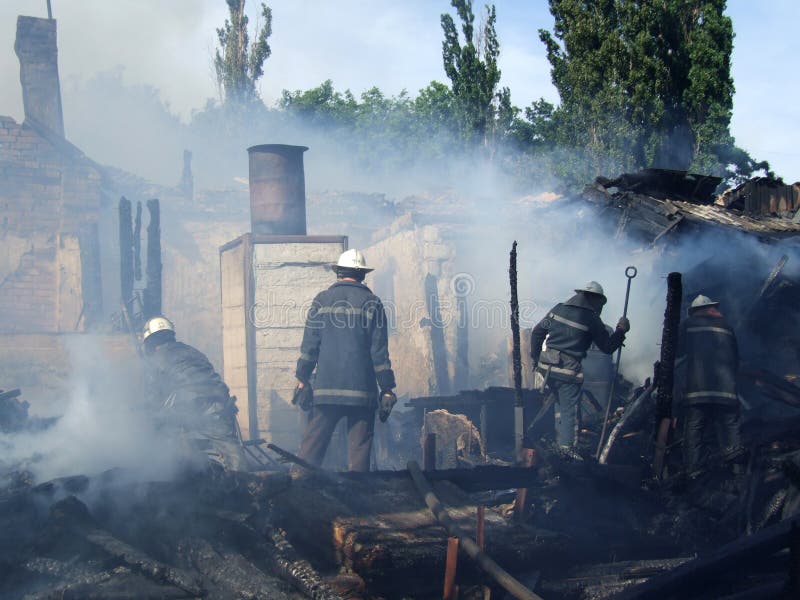 Пожарные тушат пожар в многоквартирном доме стоковое фото Пожарные тушат пожар в многоквартирном доме стоковое фото
