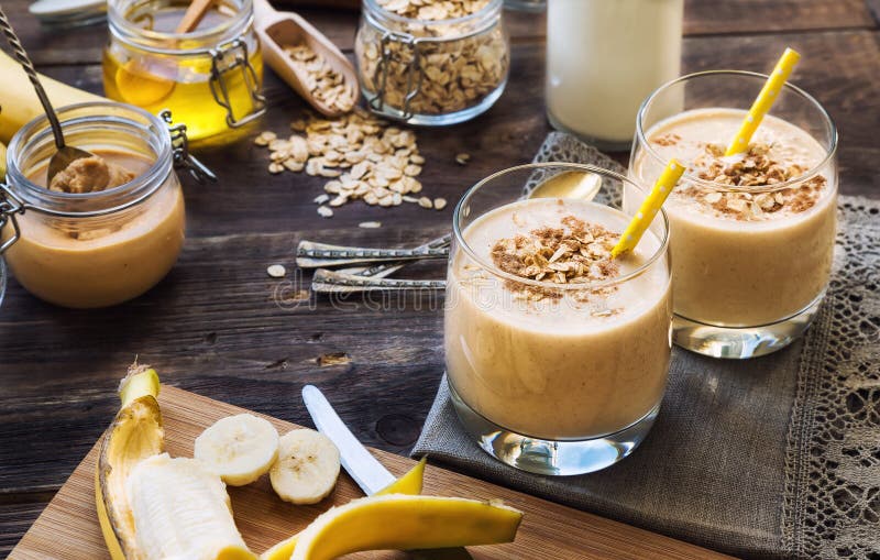 Fresh homemade nutritional smoothie with banana, oat flakes and peanut butter on rustic wooden background with ingredients. Healthy breakfast. Fresh homemade nutritional smoothie with banana, oat flakes and peanut butter on rustic wooden background with ingredients. Healthy breakfast.