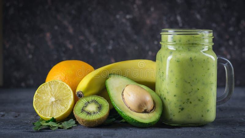 Smoothie of avocado, banana, kiwi and lemon on a wooden table against a black wall. Vegetarian food for a healthy lifestyle.
