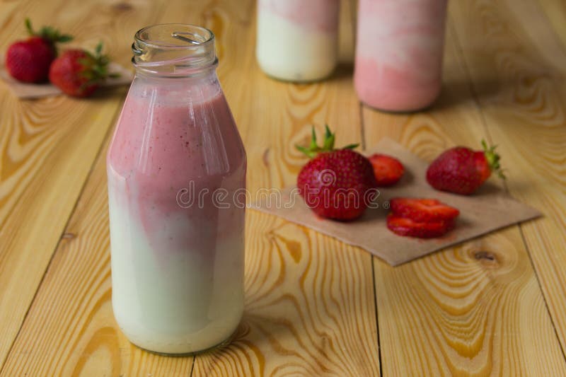 Smoothie con la fresa en botellas en la tabla de madera imagenes de archivo Smoothie con la fresa en botellas en la tabla de madera imagenes de archivo
