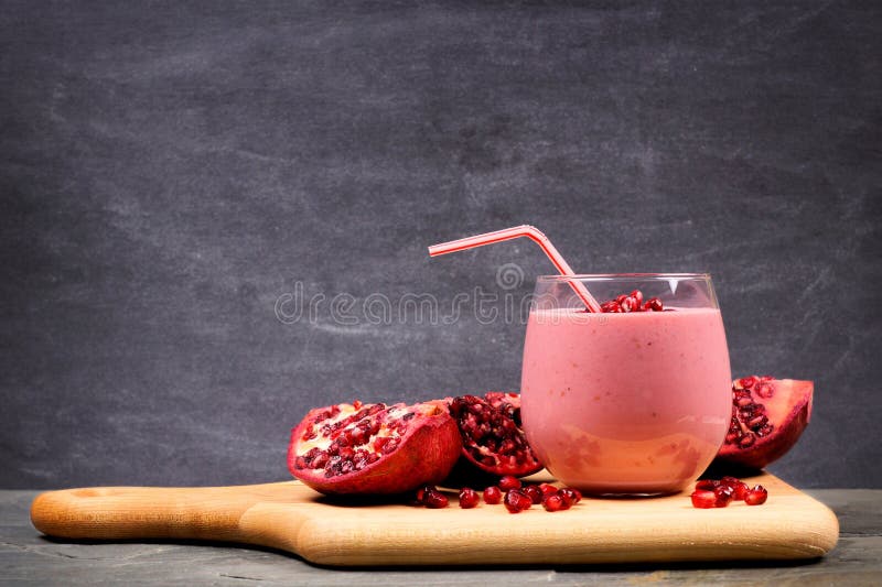 Smoothie de la frambuesa de la granada en un tablero de paleta sobre pizarra negra foto de archivo libre de regalías Smoothie de la frambuesa de la granada en un tablero de paleta sobre pizarra negra foto de archivo libre de regalías