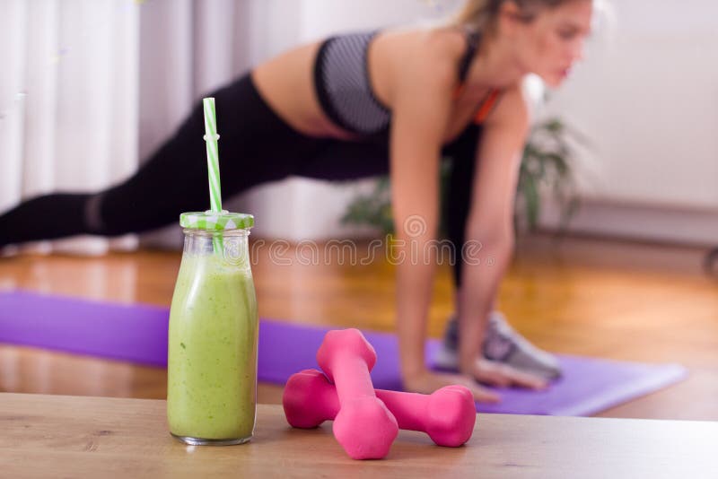 Smoothie och hantlar framme av att öva för flicka arkivbild Smoothie och hantlar framme av att öva för flicka arkivbild