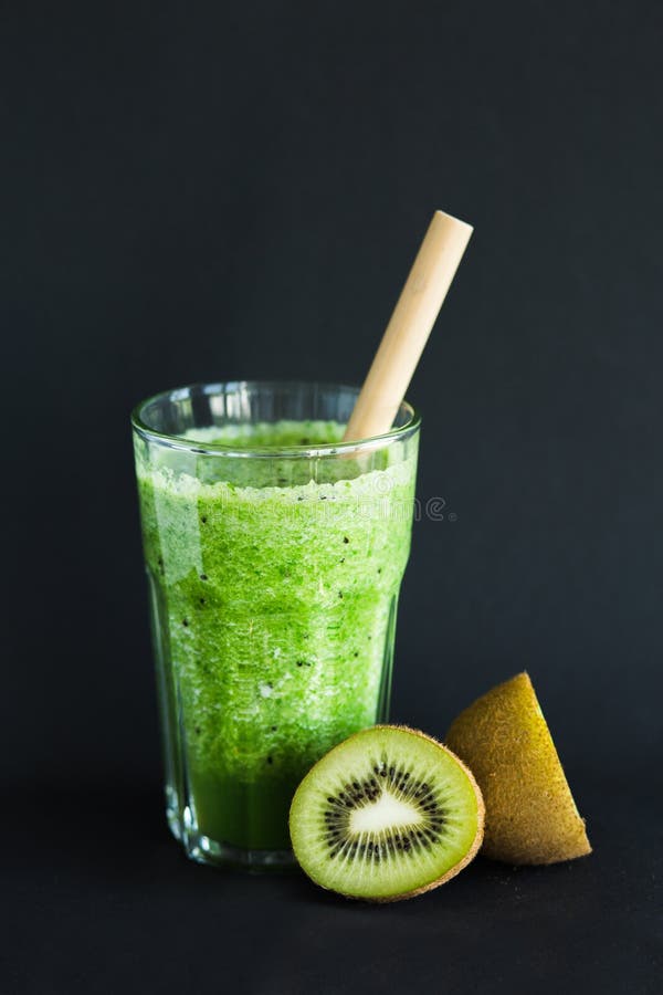 Smoothie verde sano con el kiwi en una taza de cristal en un fondo negro fotos de archivo libres de regalías Smoothie verde sano con el kiwi en una taza de cristal en un fondo negro fotos de archivo libres de regalías
