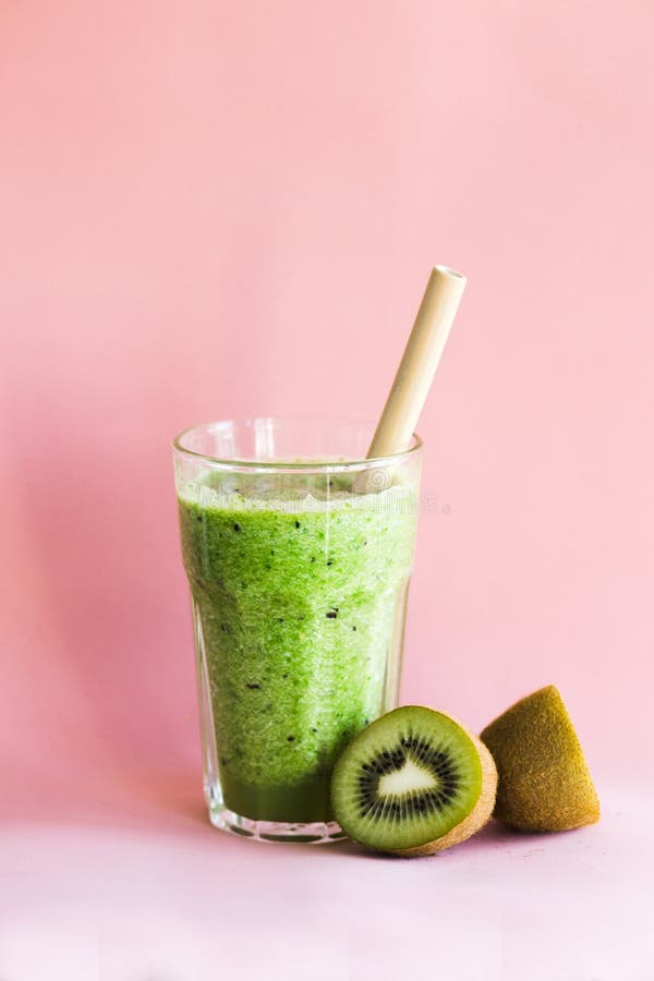 Smoothie verde sano con el kiwi en una taza de cristal en un fondo rosado fotos de archivo Smoothie verde sano con el kiwi en una taza de cristal en un fondo rosado fotos de archivo