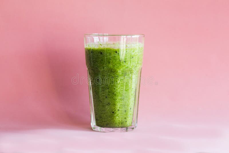 Smoothie verde sano con en una taza de cristal en un fondo rosado imágenes de archivo libres de regalías Smoothie verde sano con en una taza de cristal en un fondo rosado imágenes de archivo libres de regalías