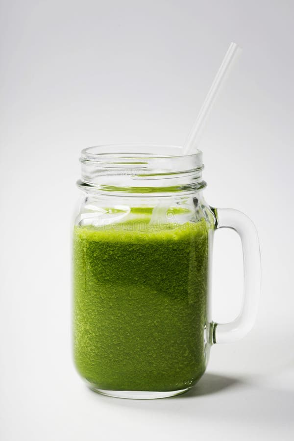 Smoothie vert sain avec la paille dans une tasse de pot image stock Smoothie vert sain avec la paille dans une tasse de pot image stock