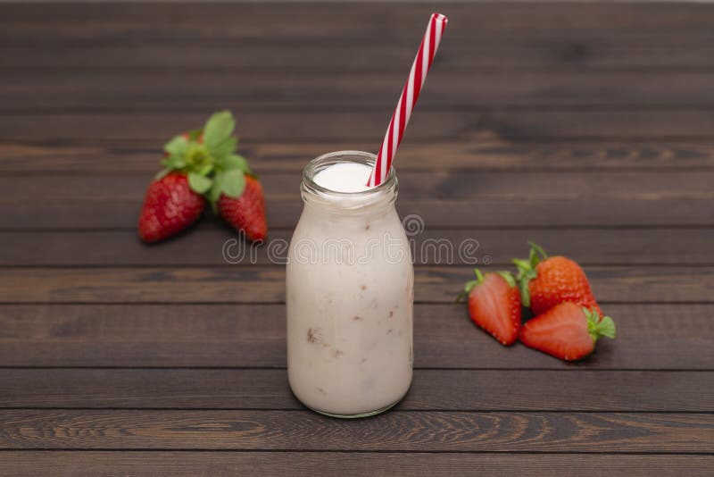 Smoothie или milkshake клубники в стеклянном опарнике с соломой со свежими ягодами на деревянной предпосылке стоковое фото Smoothie или milkshake клубники в стеклянном опарнике с соломой со свежими ягодами на деревянной предпосылке стоковое фото