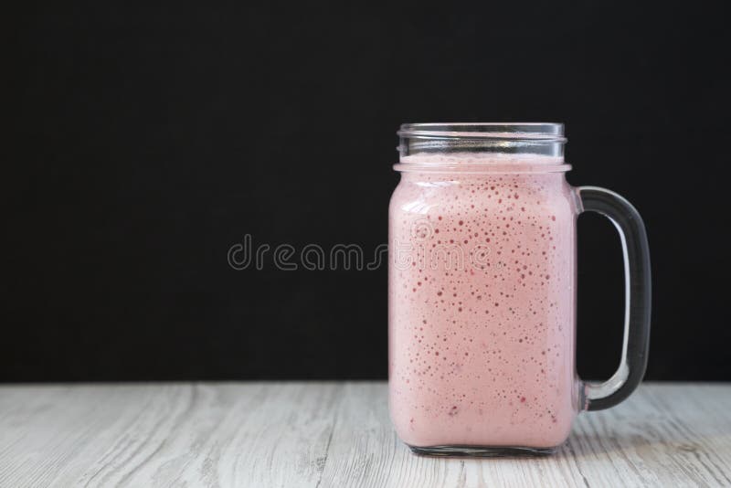 Smoothie в стеклянном опарнике, взгляд со стороны банана клубники Космос для текста стоковые фотографии rf Smoothie в стеклянном опарнике, взгляд со стороны банана клубники Космос для текста стоковые фотографии rf