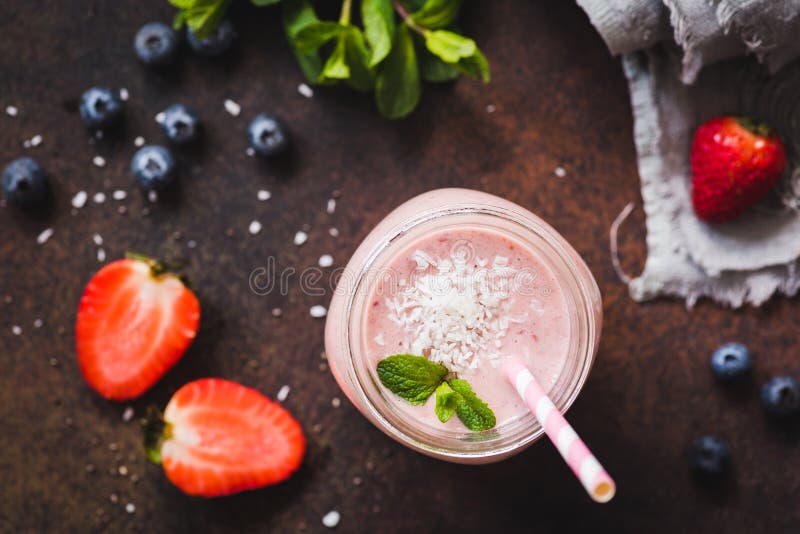 Smoothie кокоса клубники в опарнике с розовой выпивая соломой, взгляд сверху, селективным фокусом стоковое изображение Smoothie кокоса клубники в опарнике с розовой выпивая соломой, взгляд сверху, селективным фокусом стоковое изображение