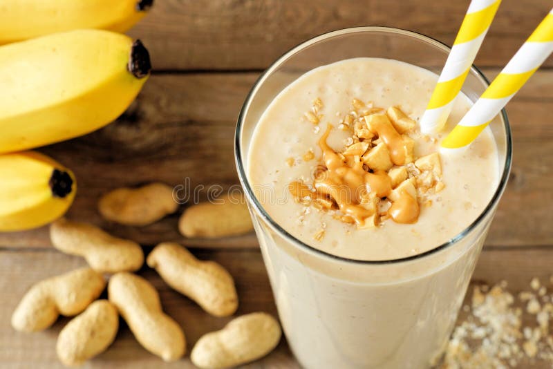 Smoothie овса банана арахисового масла на деревенской древесине с разбросанными ингридиентами стоковое фото