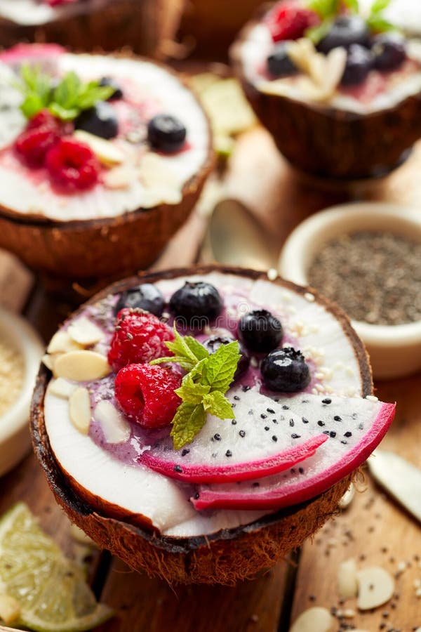 Smoothie ягоды в шаре кокоса с свежими плодоовощ дракона плодоовощ Pitaya, голубиками и полениками, мятой, миндалиной шелушится, стоковая фотография Smoothie ягоды в шаре кокоса с свежими плодоовощ дракона плодоовощ Pitaya, голубиками и полениками, мятой, миндалиной шелушится, стоковая фотография