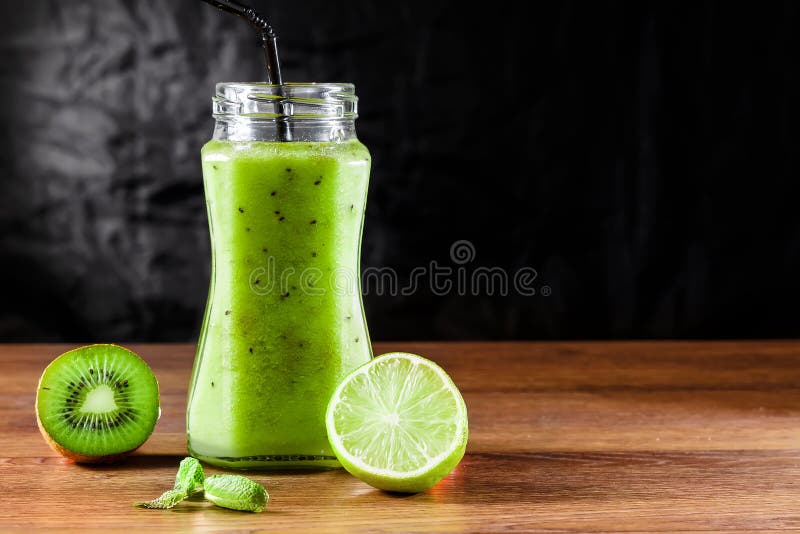 Smoothies in a glass jar of kiwi, green apple, lime, mint and avocado on a wooden table. The concept of a healthy diet, detox