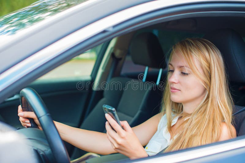 SMS de la escritura de la mujer mientras que conduce el coche imagen de archivo SMS de la escritura de la mujer mientras que conduce el coche imagen de archivo