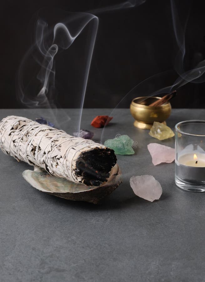 Smoking herbal incense. The smoke of palo santo stick and white sage bundle royalty free stock image