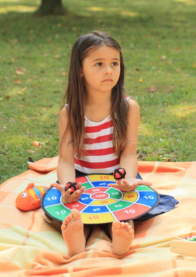 Sad sitting little barefoot girl playing with a colorful target. Sad sitting little barefoot girl playing with a colorful target