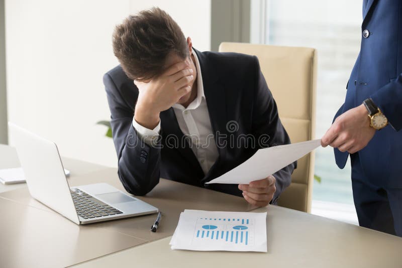 Sad manager getting notice of dismissal, sitting at workplace with laptop and financial documents, employee receiving letter with bad news, entrepreneur upset by commercial failure or firm bankruptcy. Sad manager getting notice of dismissal, sitting at workplace with laptop and financial documents, employee receiving letter with bad news, entrepreneur upset by commercial failure or firm bankruptcy