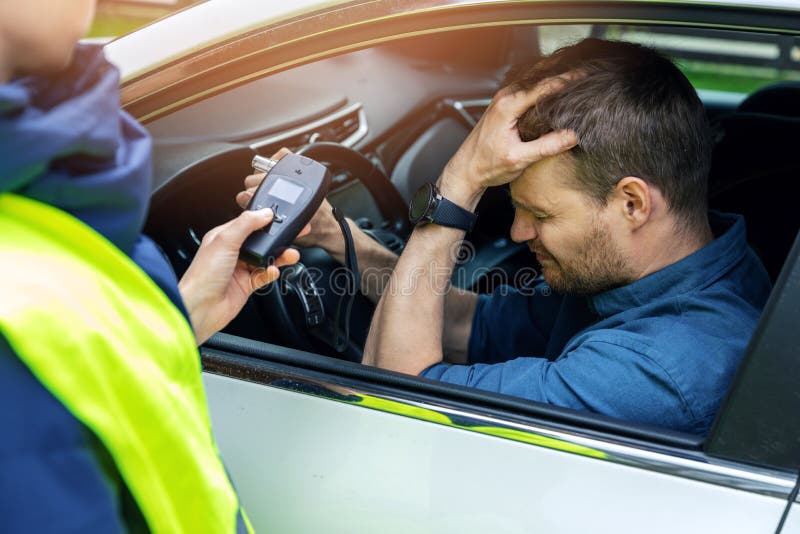 Smutny pijany mężczyzna siedzący w samochodzie po policyjnym teście alkoholowym z alcometerem