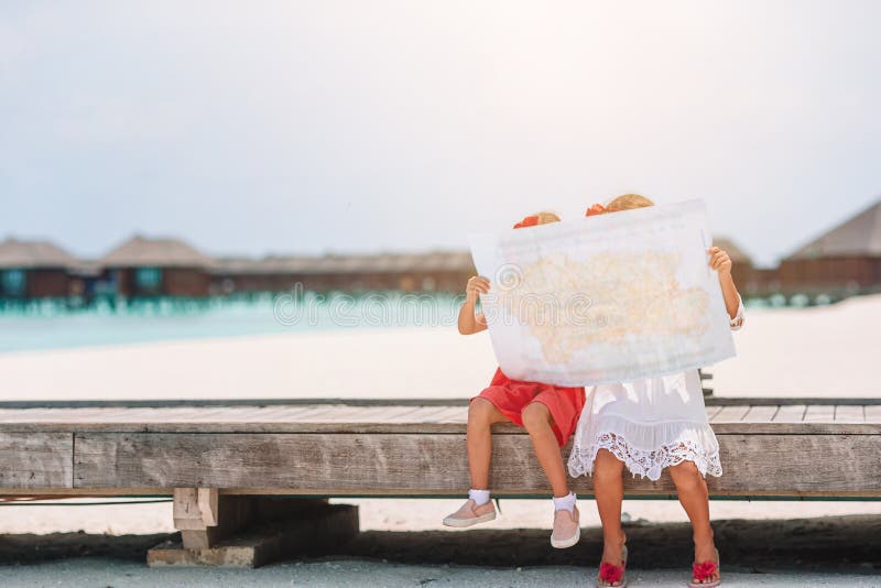 Små, vackra flickor med stor karta på tropisk strandsemester royaltyfri fotografi