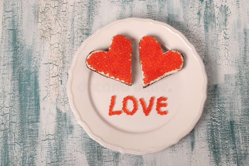 Smörgåsar med den röda kaviaren och gräddost i formen av en hjärta för valentin dag arkivbilder Smörgåsar med den röda kaviaren och gräddost i formen av en hjärta för valentin dag arkivbilder