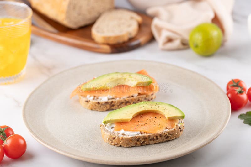 Smörost med laxavokado och krämost som serveras på en minimalistisk platta. Näringsmässiga och naturliga frukost. royaltyfri foto