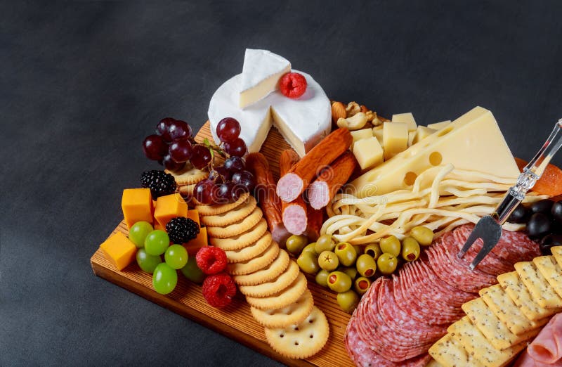 Snack set with various meat variety, cheese, crackers, green olives, nuts and berries over rustic wooden table background royalty free stock image Snack set with various meat variety, cheese, crackers, green olives, nuts and berries over rustic wooden table background royalty free stock image