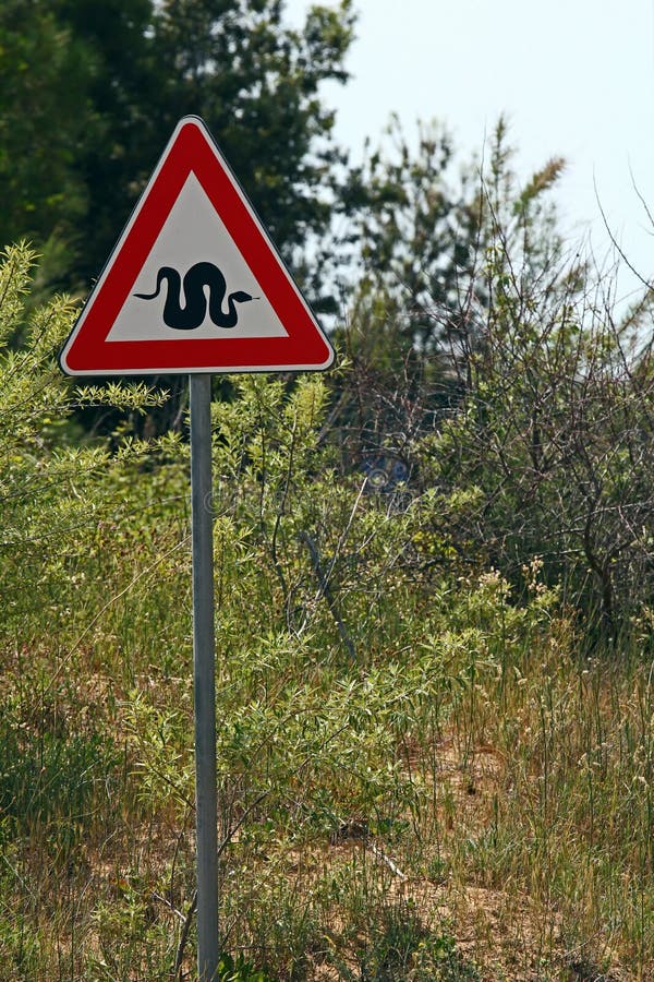 Un rosso e bianco segno su un post che è di avviso di serpenti nel bosco.