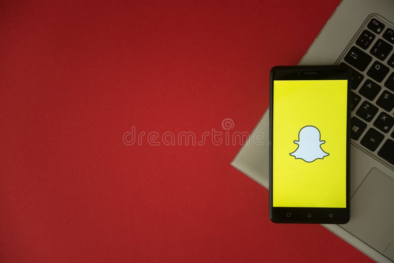 Snapchat logo on smartphone screen placed on laptop keyboard.
