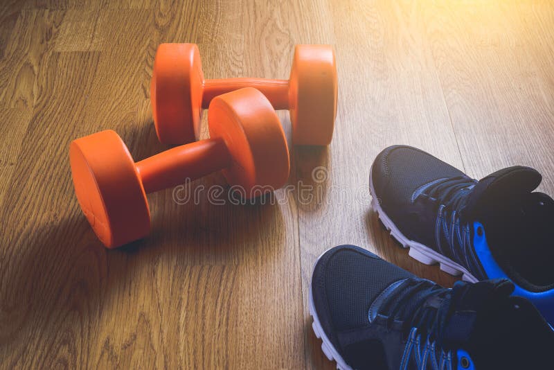 Sneakers and dumbbells fitness on a wooden background.