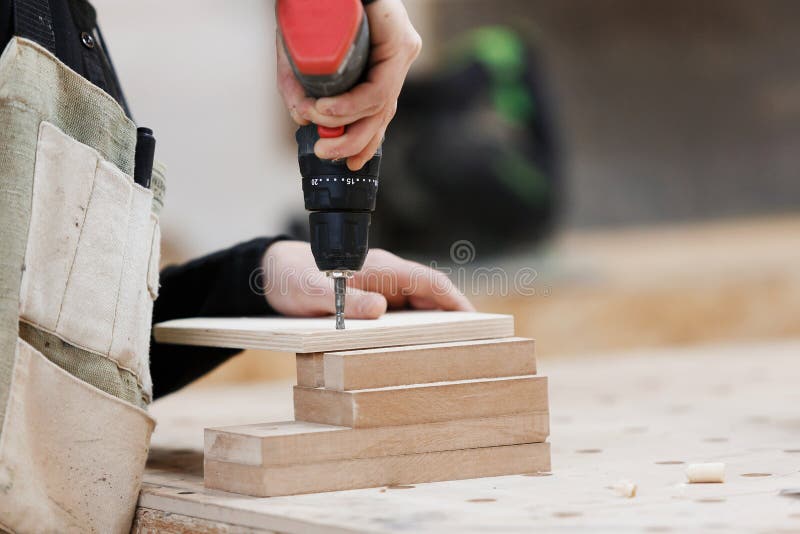 Snickare som arbetar med en elektrisk skruvmejsel p? arbetsb?nken arkivbilder Snickare som arbetar med en elektrisk skruvmejsel p? arbetsb?nken arkivbilder