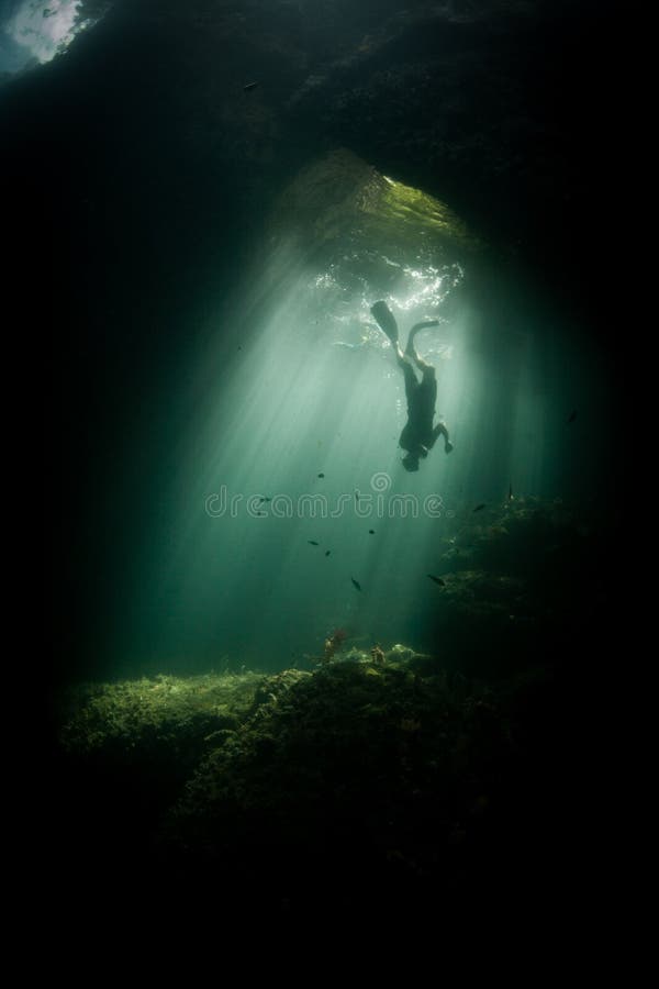 Snorkeler e luce solare in Raja Ampat Cavern scuro fotografie stock