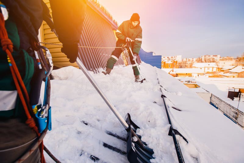 Snow cleaning. Team of male workers clean roof