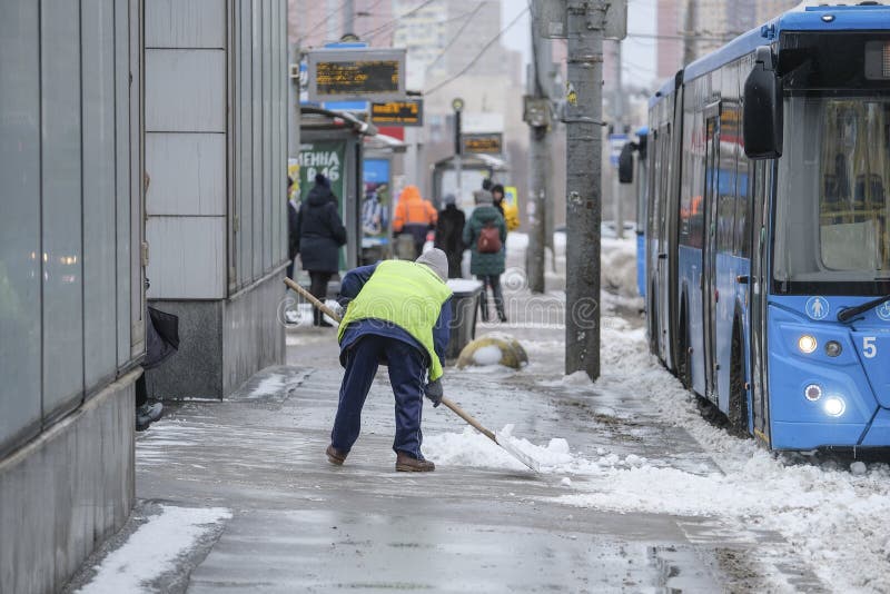 snow clearing by people from public utilities in Moscow near the bus stop stock photo snow clearing by people from public utilities in Moscow near the bus stop stock photo