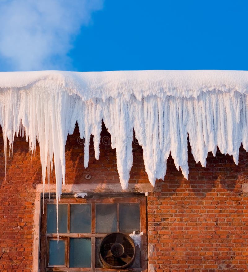 Snow cover on roof of old textile fabric with icicles, blue sky