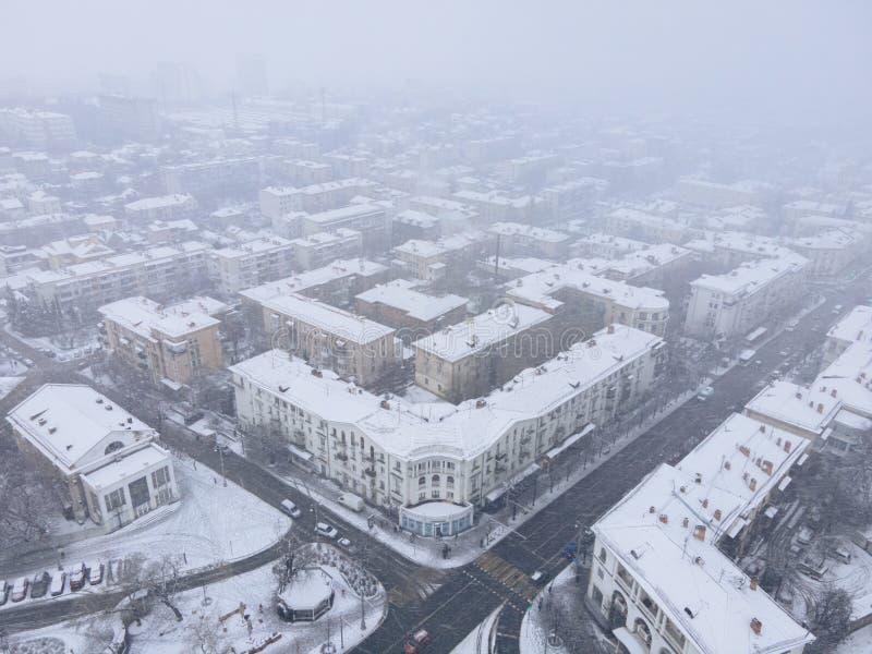 Snow-covered city square from a bird s eye view. Old streets. Roofs of houses in the snow. A white veil.