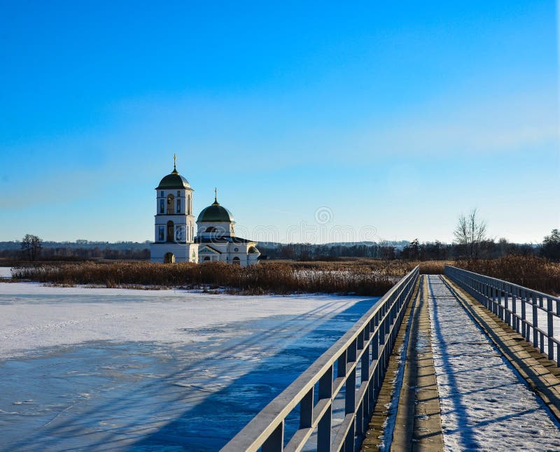 Snow-covered lake with a metal bridge towards church stock image Snow-covered lake with a metal bridge towards church stock image